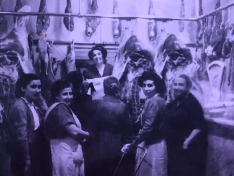 Fotografia històrica de la carnisseria Ca la Rossa amb pernils i embotits penjats