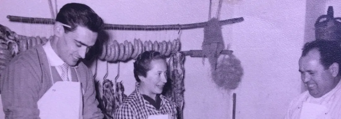 Fotografia històrica de Ca la Rossa: carnissers amb embotits penjats a la botiga
